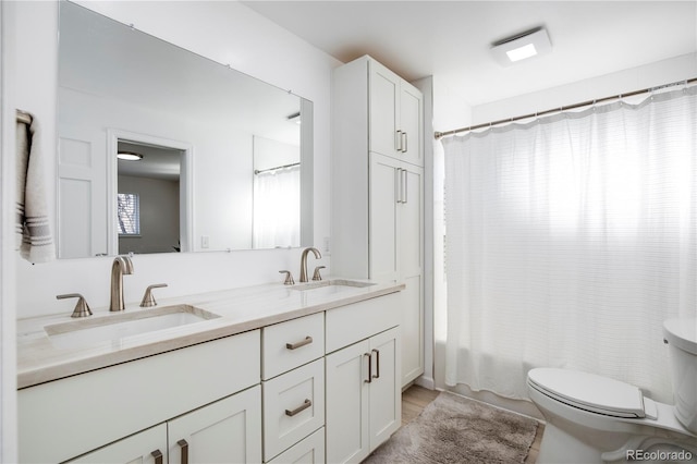 full bath with toilet, shower / bathtub combination with curtain, double vanity, and a sink