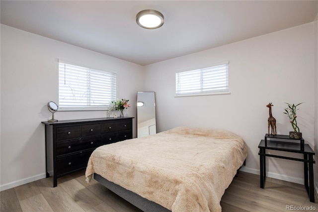 bedroom featuring light wood-style floors, multiple windows, and baseboards