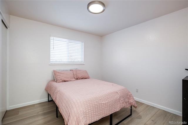 bedroom featuring a closet, light wood-type flooring, and baseboards