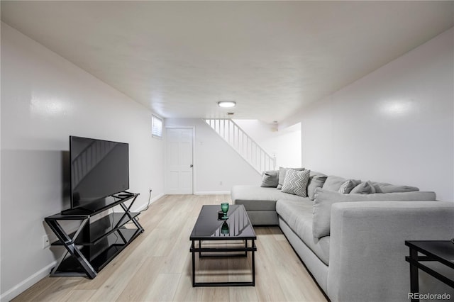 living room with light wood-type flooring, stairway, and baseboards