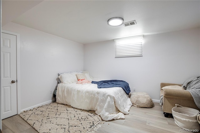 bedroom with visible vents, baseboards, and wood finished floors