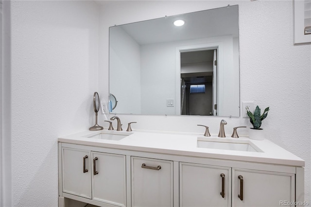 full bathroom with a textured wall, a sink, and double vanity