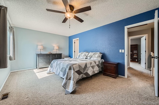 bedroom with carpet floors, visible vents, a ceiling fan, a textured ceiling, and baseboards