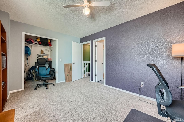 carpeted office space featuring a ceiling fan, a textured wall, a textured ceiling, and baseboards