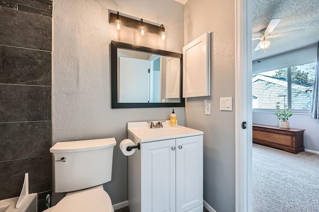 bathroom with ceiling fan, a textured wall, vanity, and toilet