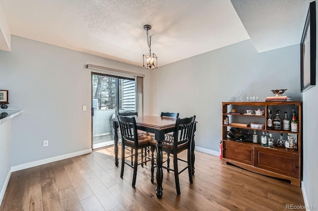 68 S Moline St, Aurora, CO 80012 - dining space featuring a textured ceiling, wood finished floors, baseboards, and a chandelier