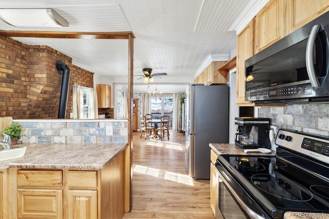 kitchen with light brown cabinetry, appliances with stainless steel finishes, brick wall, and light hardwood / wood-style flooring