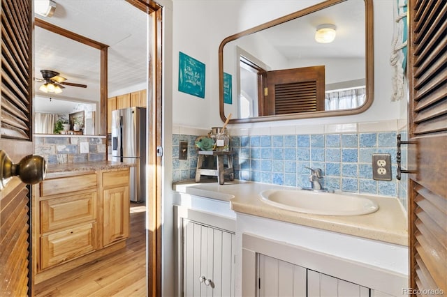 bathroom featuring ceiling fan, vanity, backsplash, and hardwood / wood-style flooring