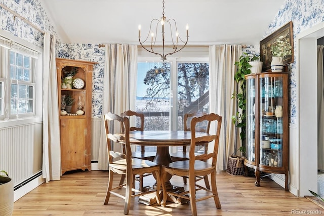 dining space featuring light wood-type flooring, a notable chandelier, vaulted ceiling, and a baseboard heating unit