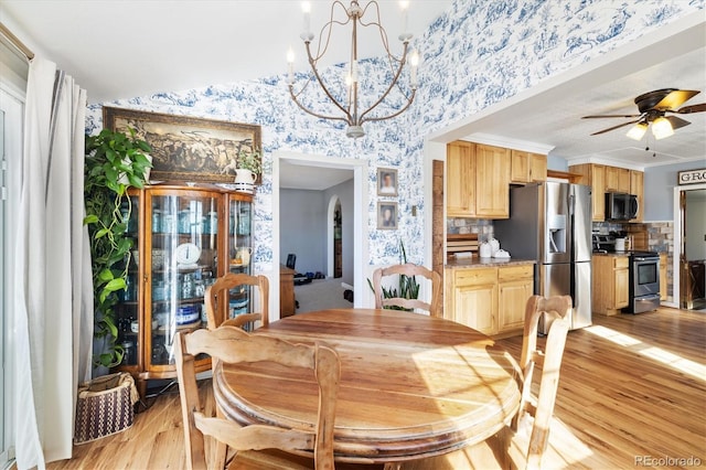 dining area featuring lofted ceiling, light wood-type flooring, and ceiling fan with notable chandelier