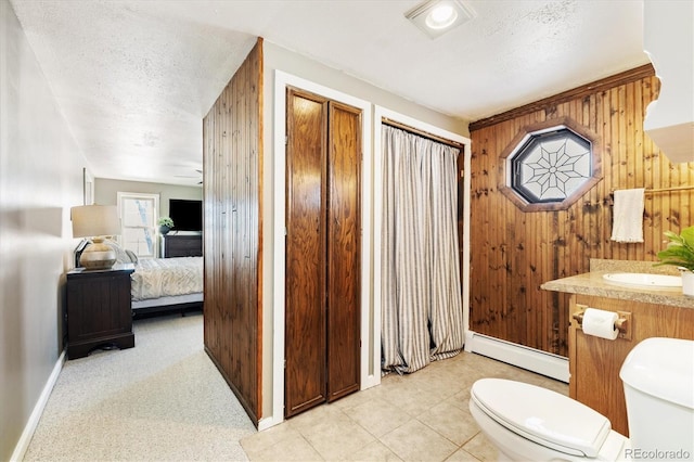 bathroom featuring a baseboard heating unit, toilet, a textured ceiling, and wood walls