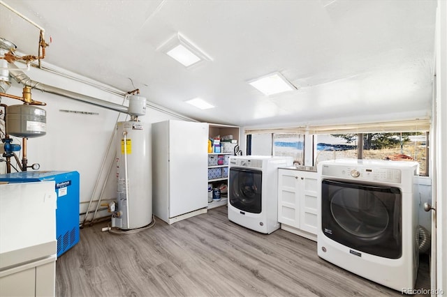 laundry area with cabinets, separate washer and dryer, light hardwood / wood-style flooring, and gas water heater