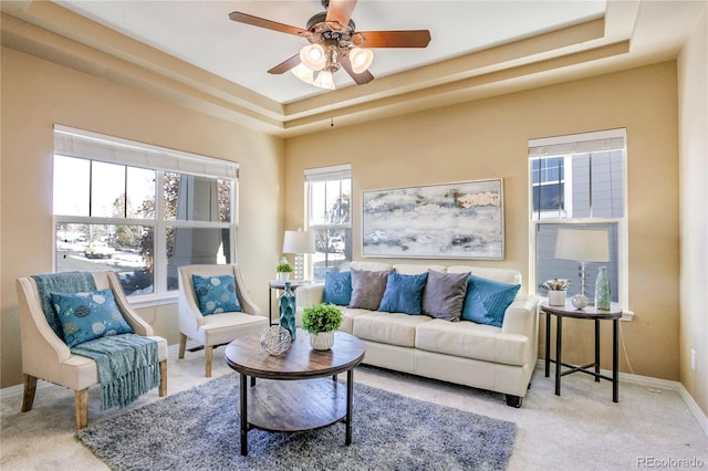 living room featuring ceiling fan, a raised ceiling, and light colored carpet