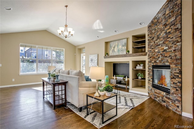 living room featuring dark hardwood / wood-style flooring, built in features, a fireplace, a notable chandelier, and lofted ceiling