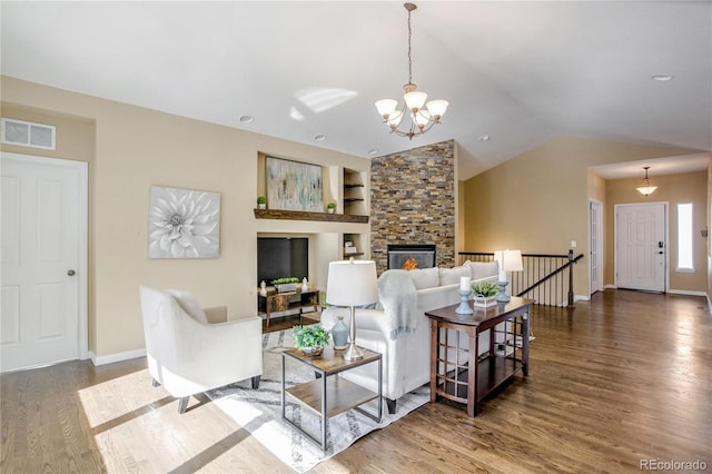 living room featuring a fireplace, built in features, a chandelier, vaulted ceiling, and hardwood / wood-style flooring