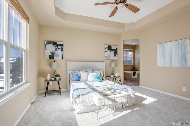 carpeted bedroom featuring ceiling fan, a raised ceiling, and multiple windows