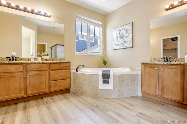 bathroom featuring vanity, hardwood / wood-style floors, and plus walk in shower