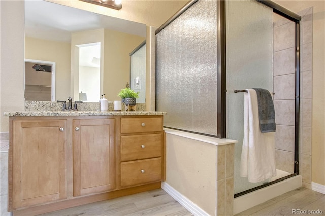 bathroom featuring hardwood / wood-style floors, an enclosed shower, and vanity