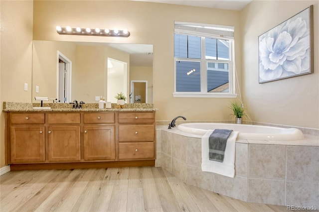 bathroom featuring vanity, hardwood / wood-style floors, and tiled bath