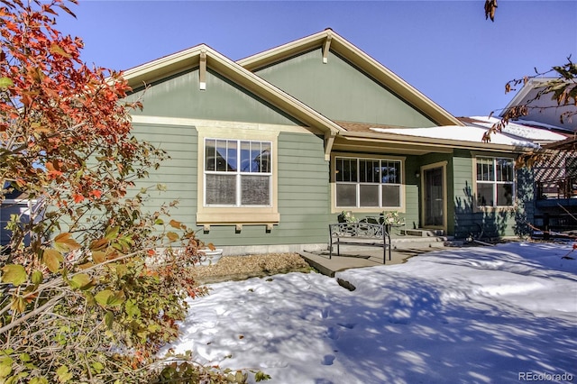 snow covered rear of property with a patio