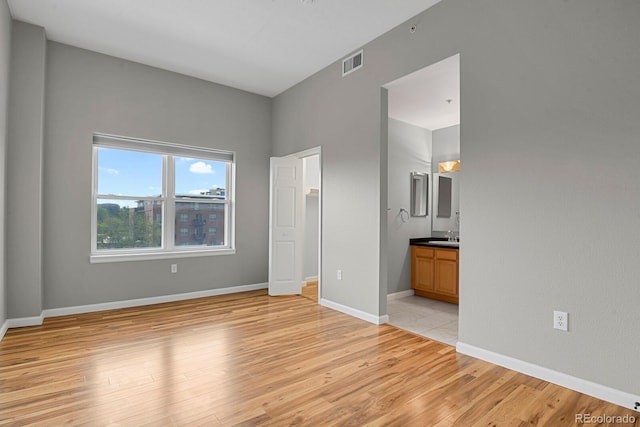 1780 N Washington St Unit 405, Denver, CO 80203 - unfurnished bedroom with light wood-style floors, a sink, baseboards, and ensuite bath