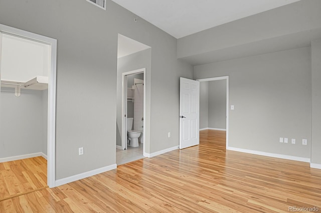 1780 N Washington St Unit 405, Denver, CO 80203 - unfurnished bedroom featuring a walk in closet, light wood-style floors, a closet, baseboards, and connected bathroom