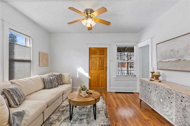 living room featuring hardwood / wood-style flooring, ceiling fan, and a textured ceiling