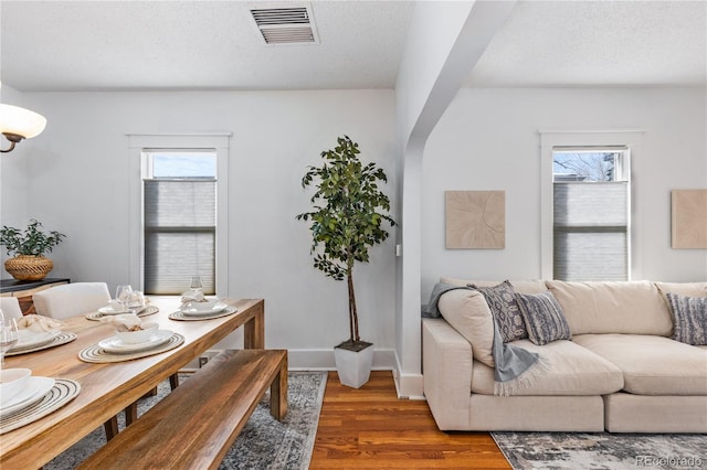 dining space with a wealth of natural light, dark hardwood / wood-style floors, and a textured ceiling