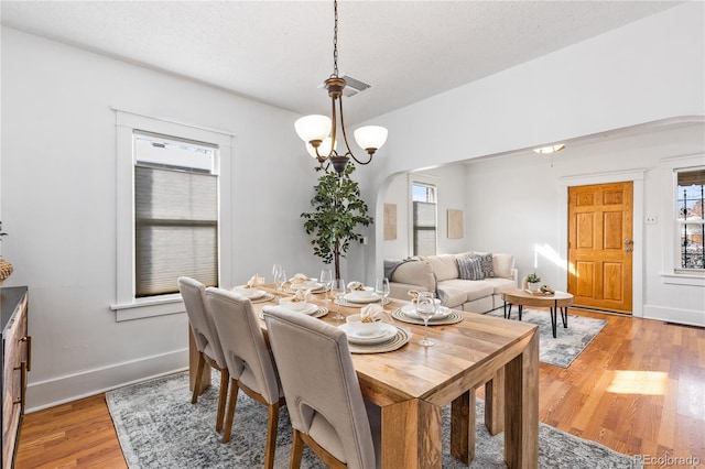 dining space featuring hardwood / wood-style flooring, a textured ceiling, and a chandelier