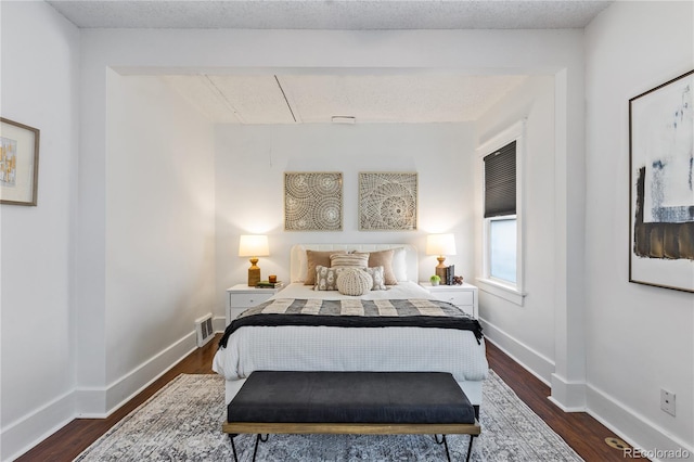 bedroom with dark hardwood / wood-style floors and a textured ceiling