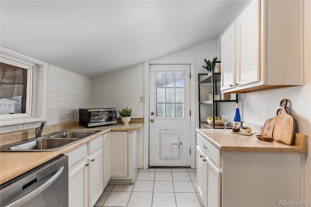 kitchen featuring sink, appliances with stainless steel finishes, backsplash, white cabinets, and light tile patterned flooring