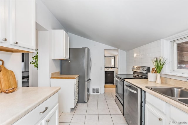 kitchen featuring appliances with stainless steel finishes, sink, white cabinets, decorative backsplash, and light tile patterned floors