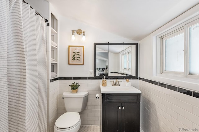 bathroom featuring lofted ceiling, vanity, toilet, and tile walls