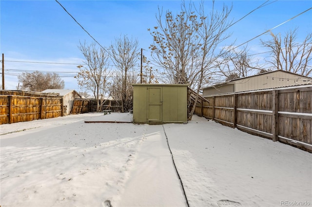 snowy yard featuring a storage unit