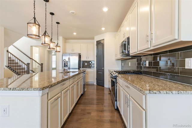 kitchen with decorative backsplash, wood-type flooring, decorative light fixtures, a center island with sink, and stainless steel appliances