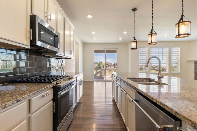 kitchen with backsplash, sink, dark hardwood / wood-style floors, stainless steel appliances, and pendant lighting