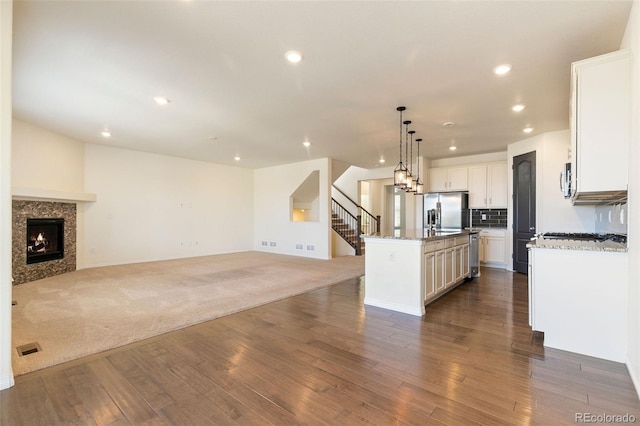 kitchen featuring a center island, decorative light fixtures, appliances with stainless steel finishes, carpet flooring, and white cabinets