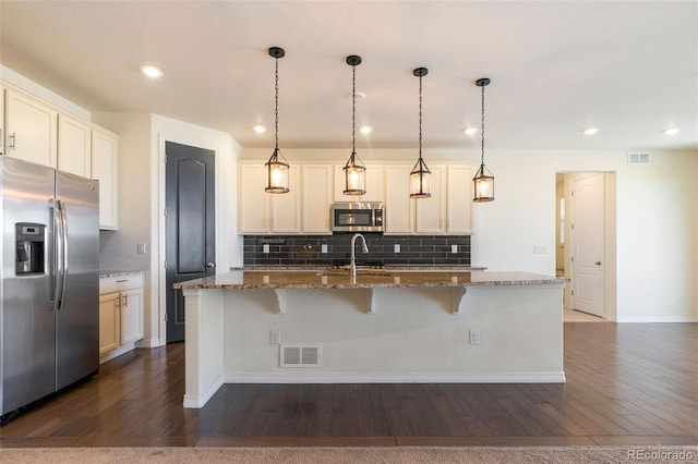 kitchen featuring appliances with stainless steel finishes, dark wood-type flooring, dark stone countertops, and decorative light fixtures