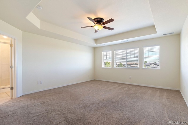 carpeted empty room with ceiling fan and a tray ceiling