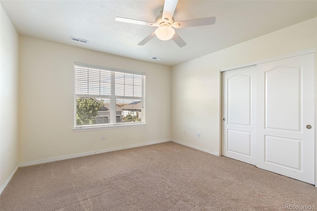 unfurnished bedroom featuring ceiling fan, light carpet, and a closet