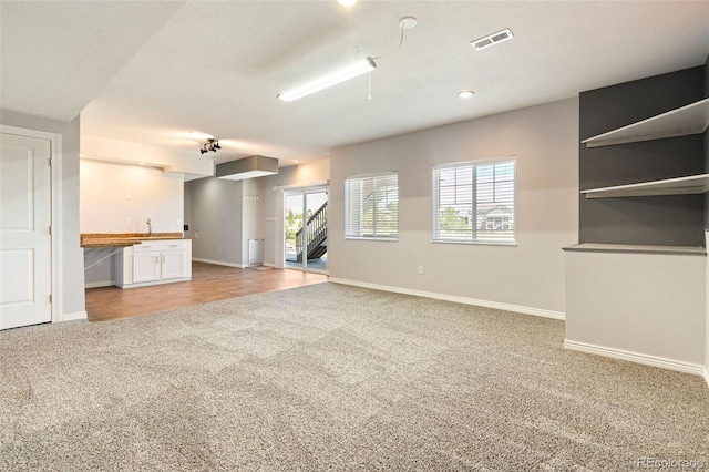 unfurnished living room featuring a healthy amount of sunlight and light colored carpet