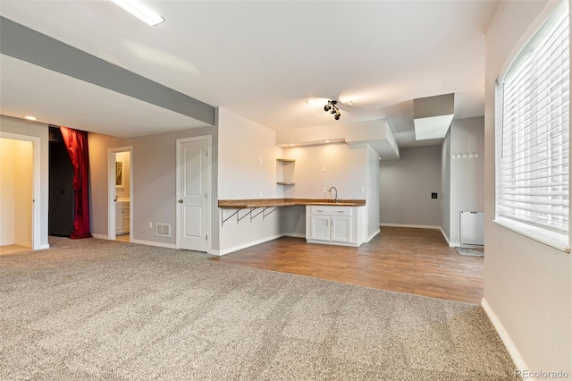 unfurnished living room with sink and light carpet