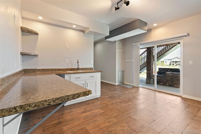 kitchen featuring rail lighting, sink, light wood-type flooring, and white cabinets