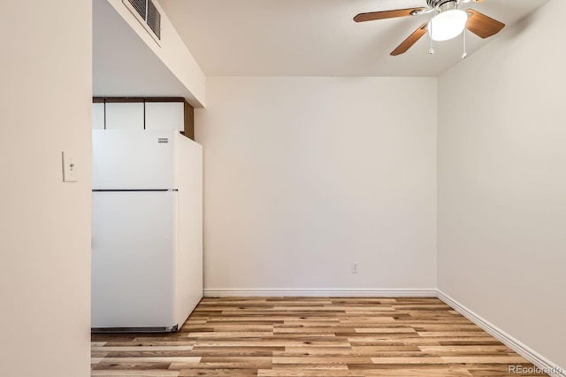 empty room featuring a ceiling fan, baseboards, visible vents, and wood finished floors