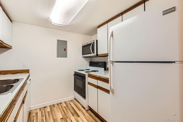 kitchen featuring light wood-style flooring, freestanding refrigerator, electric range, electric panel, and stainless steel microwave