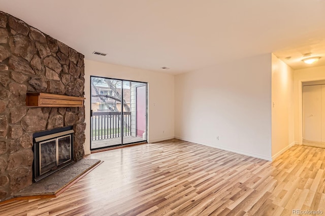 unfurnished living room featuring a fireplace, baseboards, visible vents, and wood finished floors