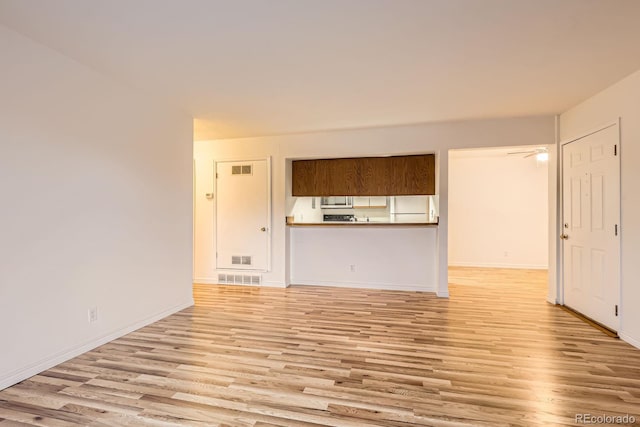 unfurnished living room with light wood-type flooring, visible vents, and baseboards