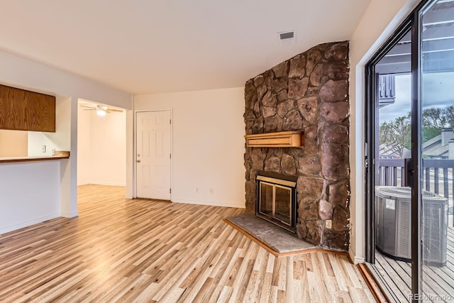 unfurnished living room featuring visible vents, wood finished floors, baseboards, and a stone fireplace