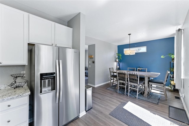 10116 Wyandott Cir, Denver, CO 80260 - kitchen featuring stainless steel fridge, light wood-type flooring, white cabinetry, light stone countertops, and decorative light fixtures