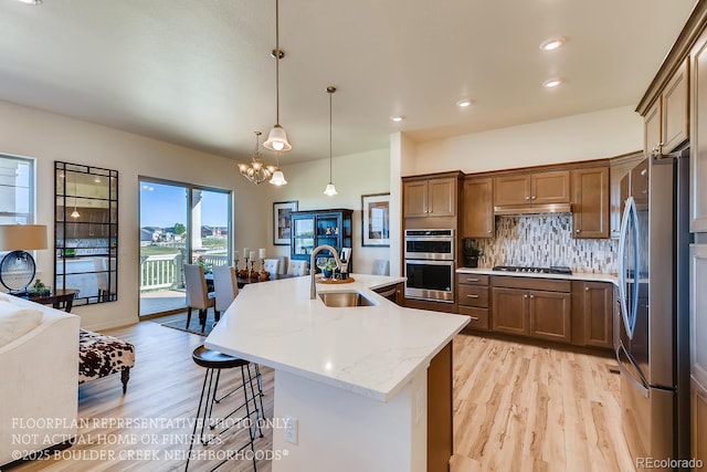 935 W 128th Pl, Westminster, CO 80234 - kitchen featuring stainless steel appliances, light wood-type flooring, a chandelier, brown cabinets, and recessed lighting